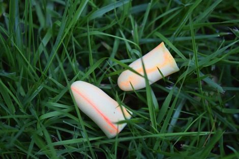 Yellow foam earplugs discarded in grass